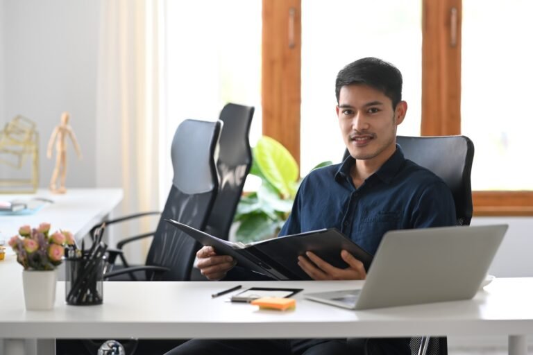 Confident investment adviser sitting in modern office and smiling to camera.