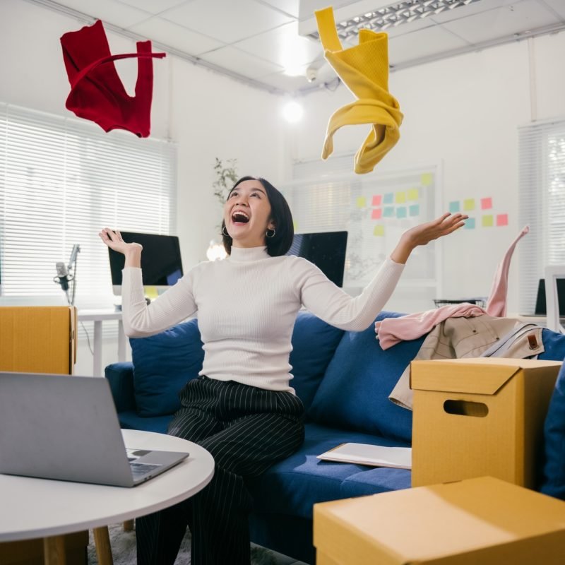 Excited businesswoman throwing clothes in the air after successful online business deal